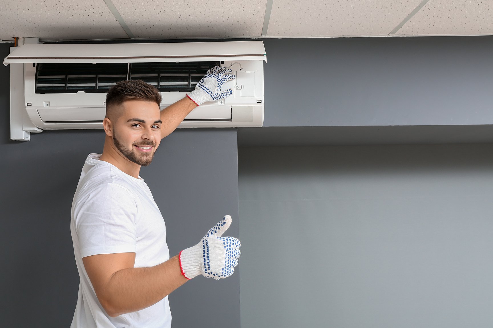 Male Technician Repairing Air Conditioner Indoors